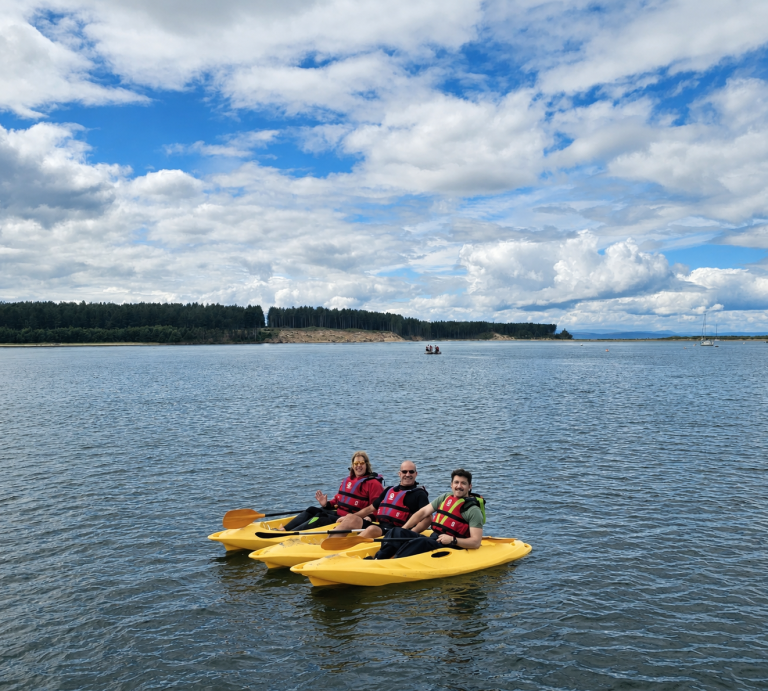 Three people kayaking on calm lake