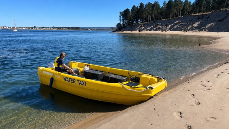 Yellow water taxi boat moored on sandy beach