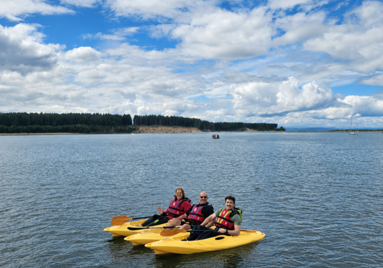 Three people kayaking on calm lake