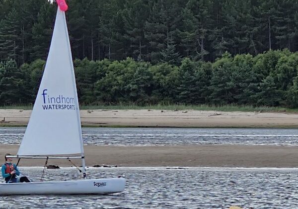 Sailboat on lake near forested coast with buoy