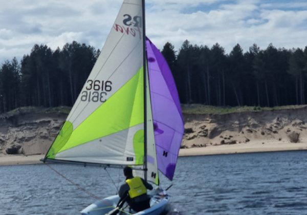 Sailboat with colorful sail navigating on calm water
