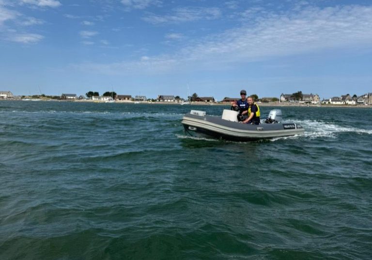 Two people on small boat at sea near coastal town