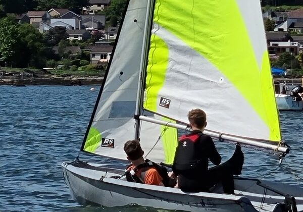 Two boys sailing on green-sailed boat