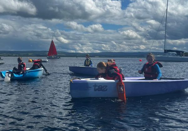 Children sailing small boats on a sunny lake