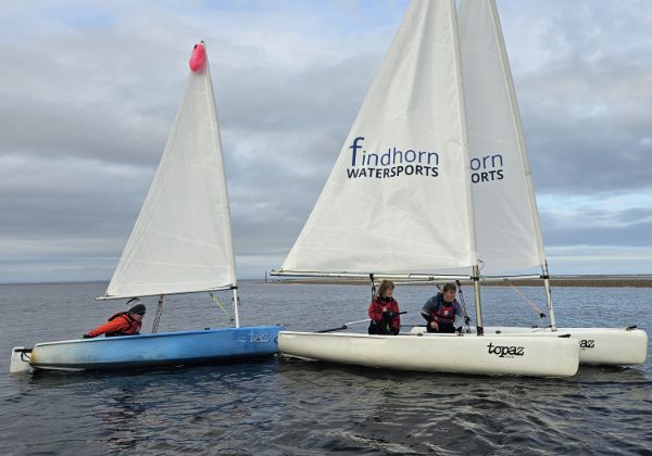 Sailboats on water with Findhorn Watersports logos
