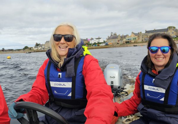 Two women enjoying boating, coastal town background