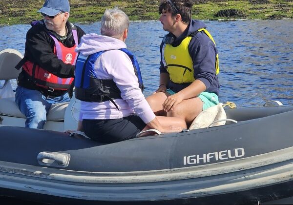 Three people conversing on a small boat in river