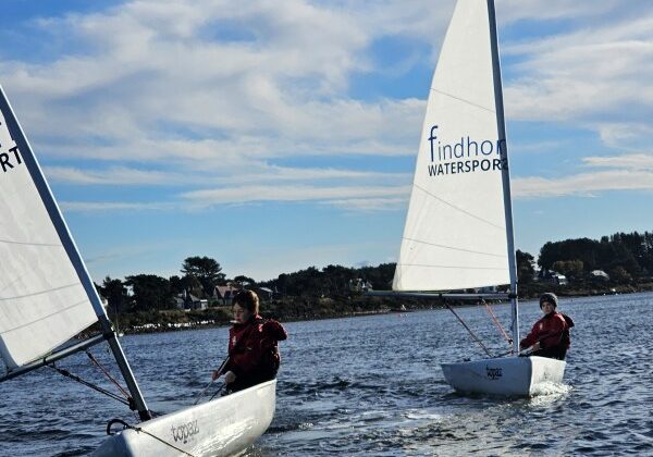 Sailors racing small boats on sunny day
