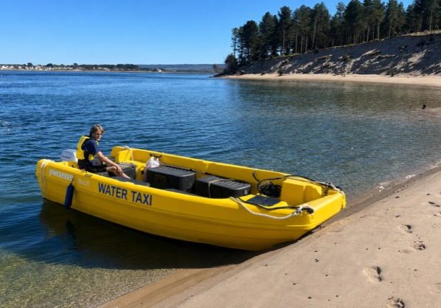 Yellow water taxi boat moored on sandy beach