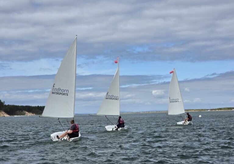 Three dinghies sailing on coastal waters