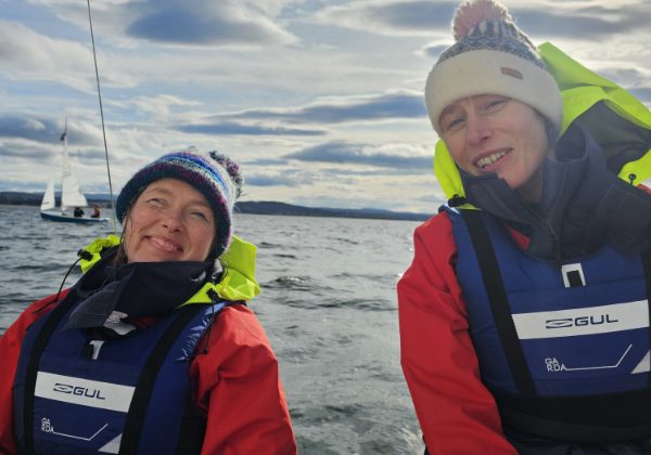 Two women sailing, wearing life jackets and knit hats